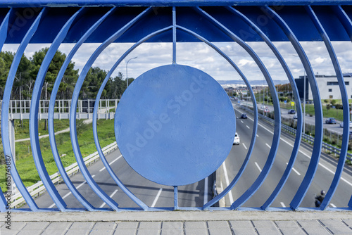 A metal railing with a peculiar structure painted blue on an access highway to the city