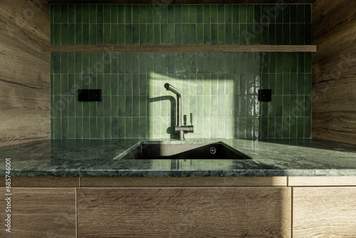 Sink in a designer kitchen with a green marble countertop, tiles on the backsplash, black taps and wooden furniture