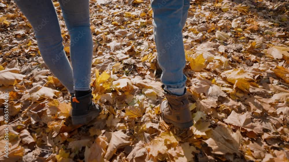 Man and woman in boots step on ground covered with fallen leaves Man and woman in boots step on ground covered with fallen leaves