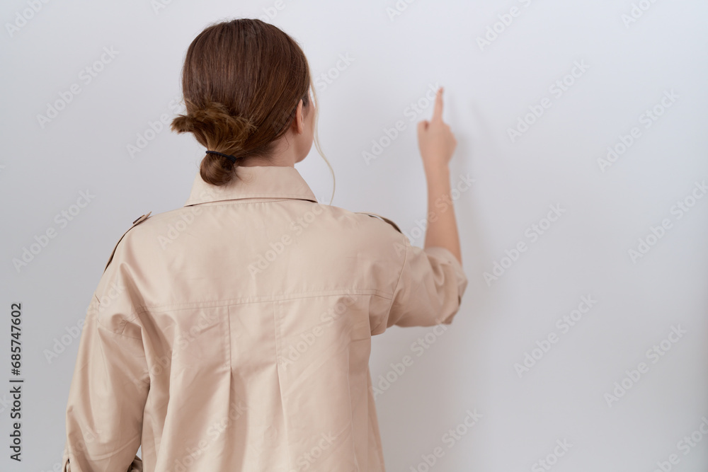 Young caucasian woman wearing casual shirt posing backwards pointing ahead with finger hand Young caucasian woman wearing casual shirt posing backwards pointing ahead with finger hand