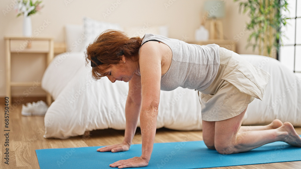Middle age woman stretching back sitting on yoga mat at bedroom Middle age woman stretching back sitting on yoga mat at bedroom