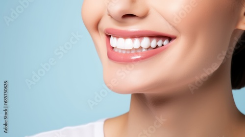 Beautiful woman's smile with healthy white, straight teeth close-up on light-blue background with space for text