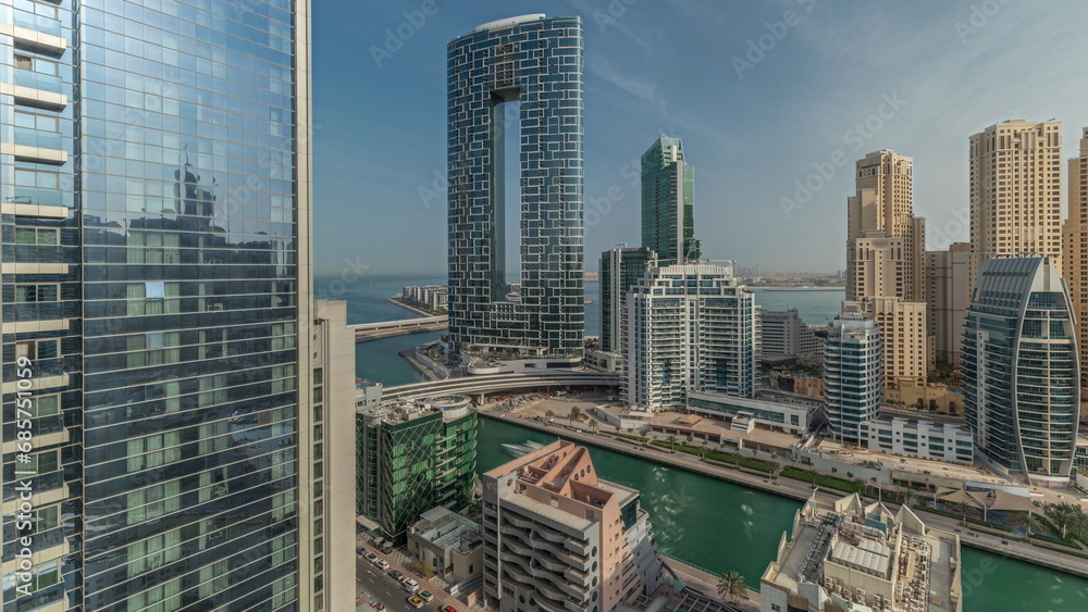 Obraz premium Panorama showing Dubai Marina with several boats and yachts parked in harbor and skyscrapers around canal aerial morning timelapse.