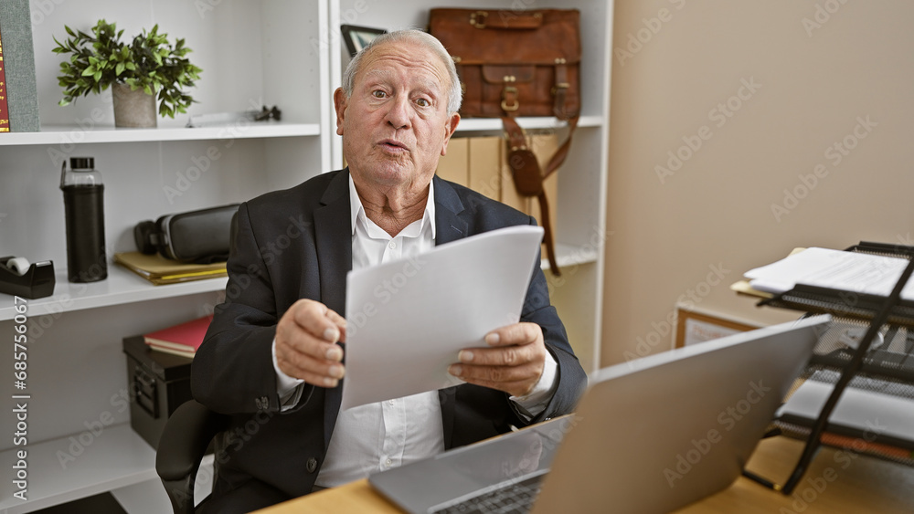 Serious, mature gentleman hard at work, elegant white-haired senior man, a seasoned business professional, engrossed in documents while speaking earnestly at the office. Serious, mature gentleman hard at work, elegant white-haired senior man, a seasoned business professional, engrossed in documents while speaking earnestly at the office.