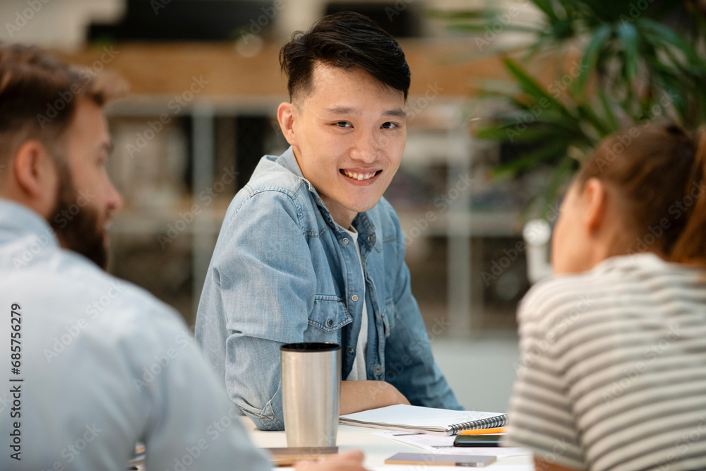 Young adult male architect looking at the camera while sitting at table Young adult male architect looking at the camera while sitting at table