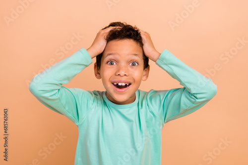 Photo of overjoyed cheerful glad boy wear trendy turquoise clothes unexpected unbelievable success isolated on beige color background