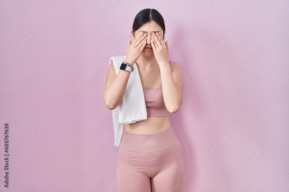Chinese young woman wearing sportswear and towel rubbing eyes for fatigue and headache, sleepy and tired expression. vision problem Chinese young woman wearing sportswear and towel rubbing eyes for fatigue and headache, sleepy and tired expression. vision problem