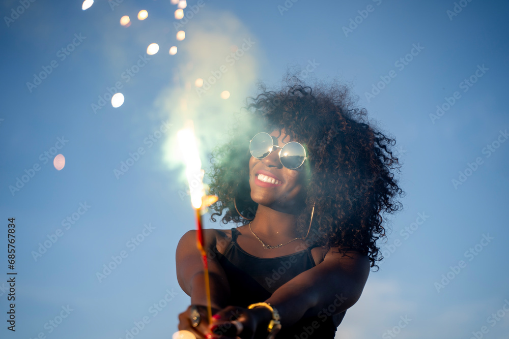 Fototapeta premium Black skinned woman using fireworks sparkler