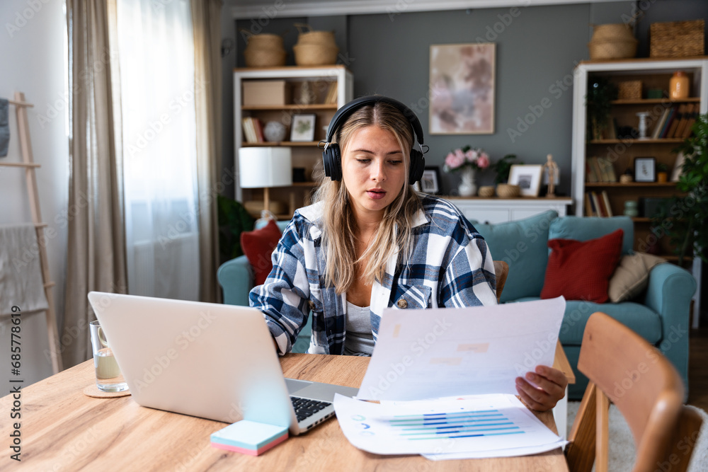 Happy woman wearing wireless headphones working on laptop at home office. Business female startup small company owner work on internet on computer. Happy woman wearing wireless headphones working on laptop at home office. Business female startup small company owner work on internet on computer.