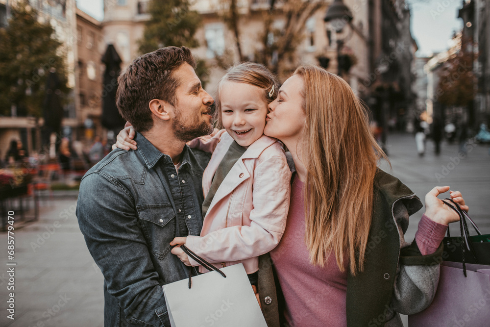 Smiling young parents with little daughter downtown in city Smiling young parents with little daughter downtown in city