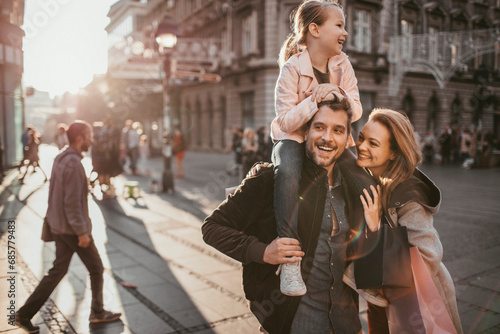 Smiling young parents with little daughter downtown in city photo