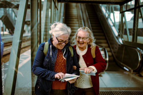 Two senior women looking at map in train station photo