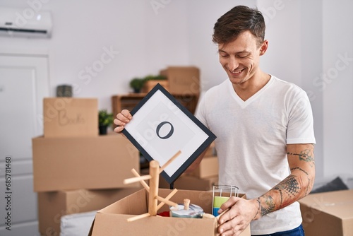 Young man smiling confident unpacking cardboard box at new home © Krakenimages.com