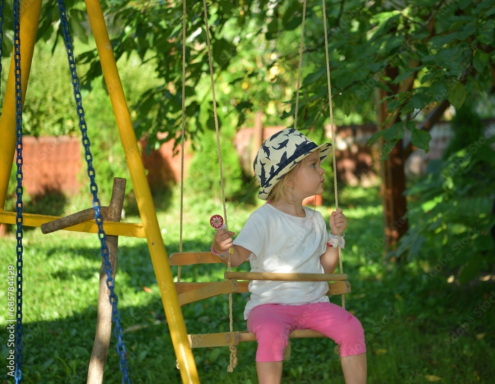 A girl licking sweet sticks on a swing on a cherry tree