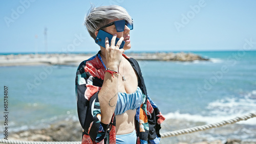 Young woman tourist wearing bikini and sunglasses talking on smartphone at beach