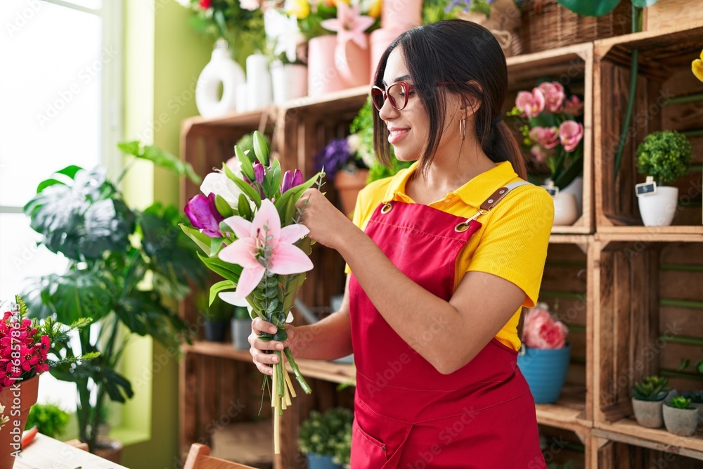 Young beautiful arab woman florist holding bouquet of flowers at flower shop