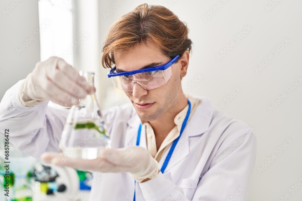 Young caucasian man scientist holding test tube with plant at laboratory Young caucasian man scientist holding test tube with plant at laboratory
