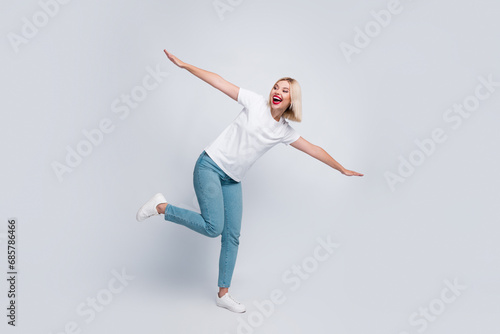 Full length photo of overjoyed girl with bob hair dressed white t-shirt flying look at sale empty space isolated on gray color background