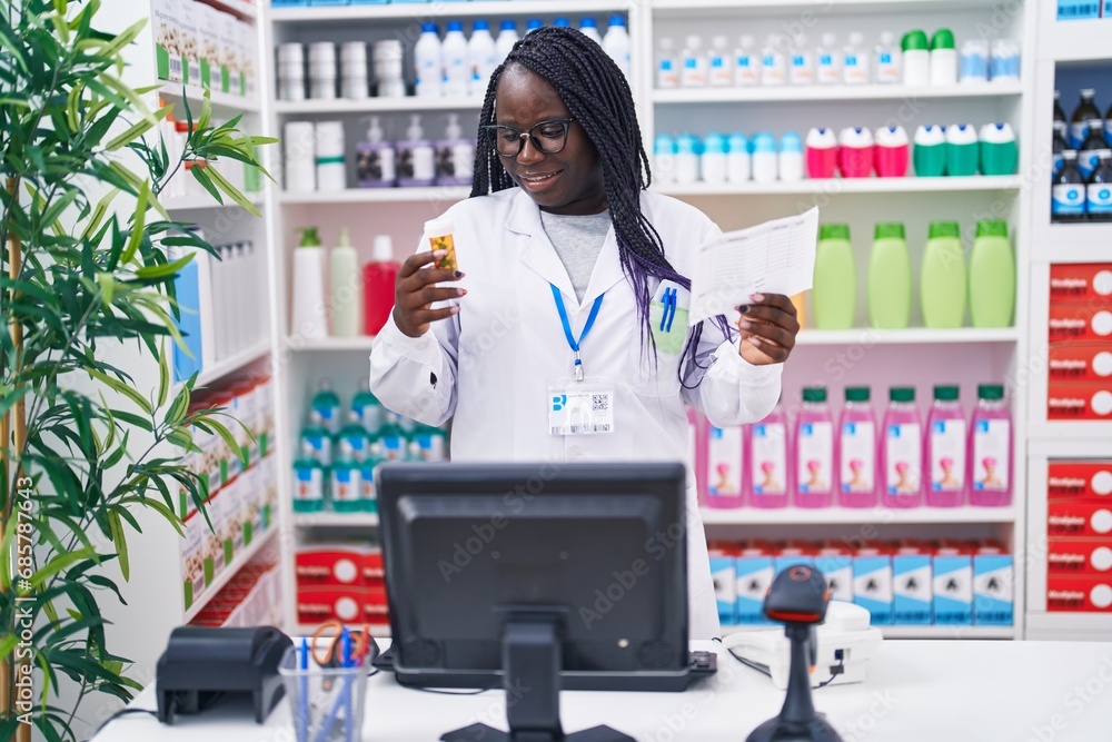 African american woman pharmacist holding pills bottle reading prescription at pharmacy African american woman pharmacist holding pills bottle reading prescription at pharmacy