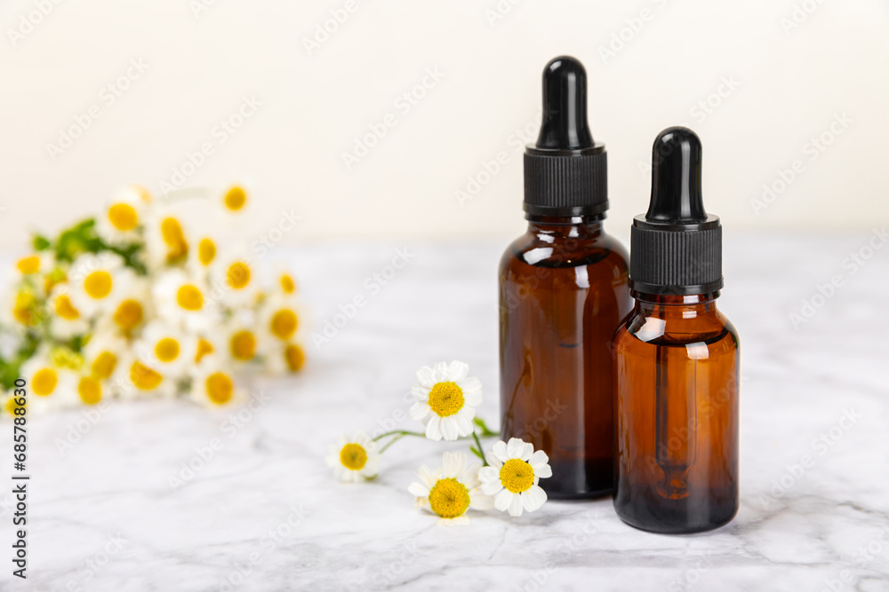 Glass bottle with chamomile essential oil on an old wooden background. Chamomile flowers, close up. Aromatherapy, spa and herbal medicine ingredients. Beauty concept.Copy space. Natural cosmetic Glass bottle with chamomile essential oil on an old wooden background. Chamomile flowers, close up. Aromatherapy, spa and herbal medicine ingredients. Beauty concept.Copy space. Natural cosmetic
