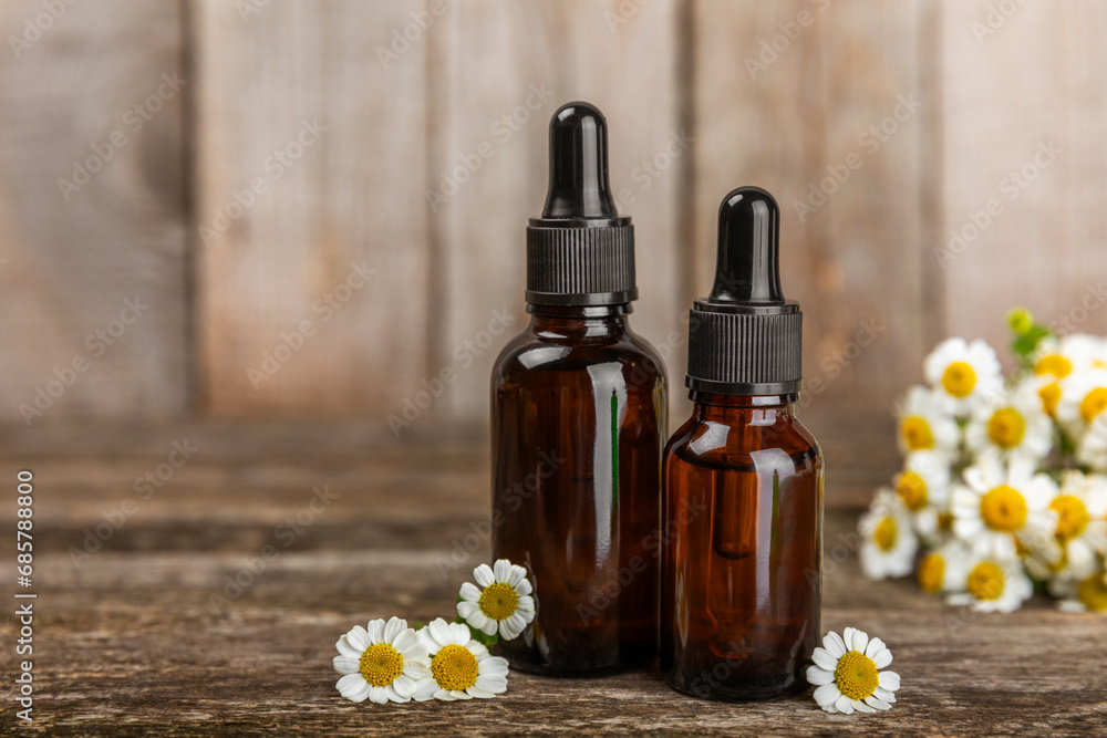 Glass bottle with chamomile essential oil on an old wooden background. Chamomile flowers, close up. Aromatherapy, spa and herbal medicine ingredients. Beauty concept.Copy space. Natural cosmetic Glass bottle with chamomile essential oil on an old wooden background. Chamomile flowers, close up. Aromatherapy, spa and herbal medicine ingredients. Beauty concept.Copy space. Natural cosmetic