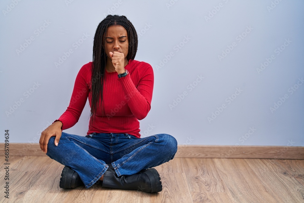 Young african american with braids sitting on the floor at home feeling unwell and coughing as symptom for cold or bronchitis. health care concept. Young african american with braids sitting on the floor at home feeling unwell and coughing as symptom for cold or bronchitis. health care concept.