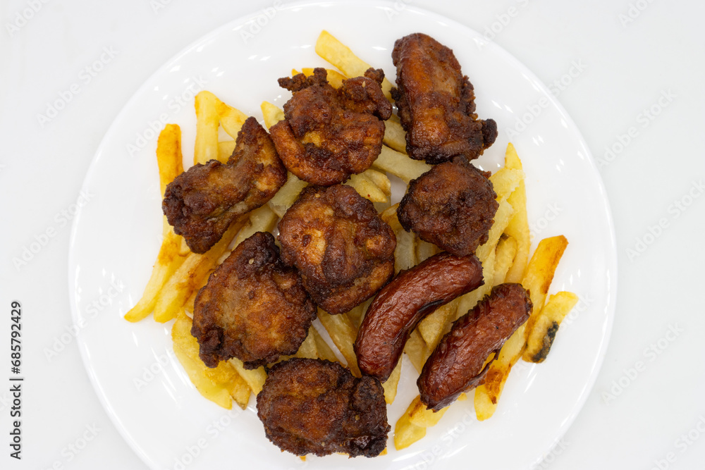 An Overhead View of Japanese Karaage Fried Chicken with Fries and Sausage on a White Plate An Overhead View of Japanese Karaage Fried Chicken with Fries and Sausage on a White Plate