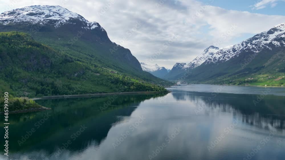 Norwegian fjord with reflective snowy mountains and cruise ship. Olden town filmed by drone in 4K. Norwegian fjord with reflective snowy mountains and cruise ship. Olden town filmed by drone in 4K.