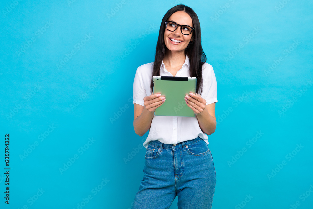 Photo of cute charming girl dressed white shirt eyewear texting modern device looking empty space isolated blue color background Photo of cute charming girl dressed white shirt eyewear texting modern device looking empty space isolated blue color background