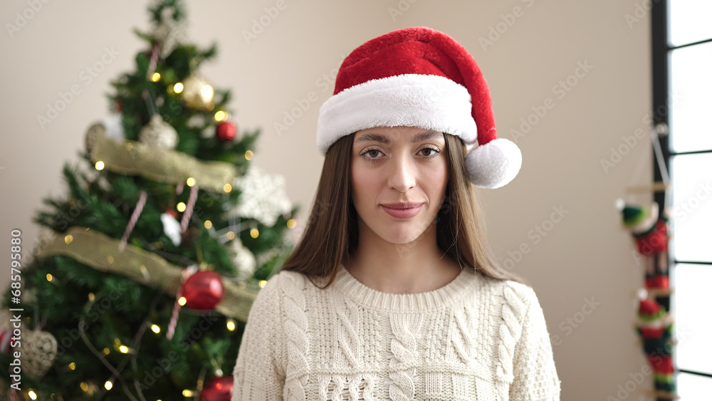 Young beautiful hispanic woman standing by christmas tree with relaxed expression at home Young beautiful hispanic woman standing by christmas tree with relaxed expression at home