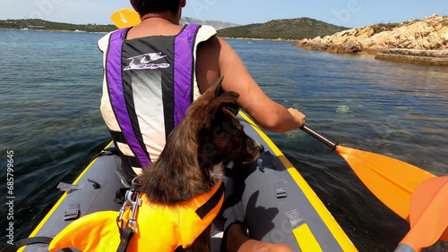 Young man and a dog on a kayak in Mediterranean Sea of Sardinia, Italy