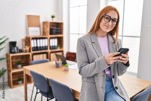 Young caucasian woman business worker smiling confident using smartphone at office © Krakenimages.com