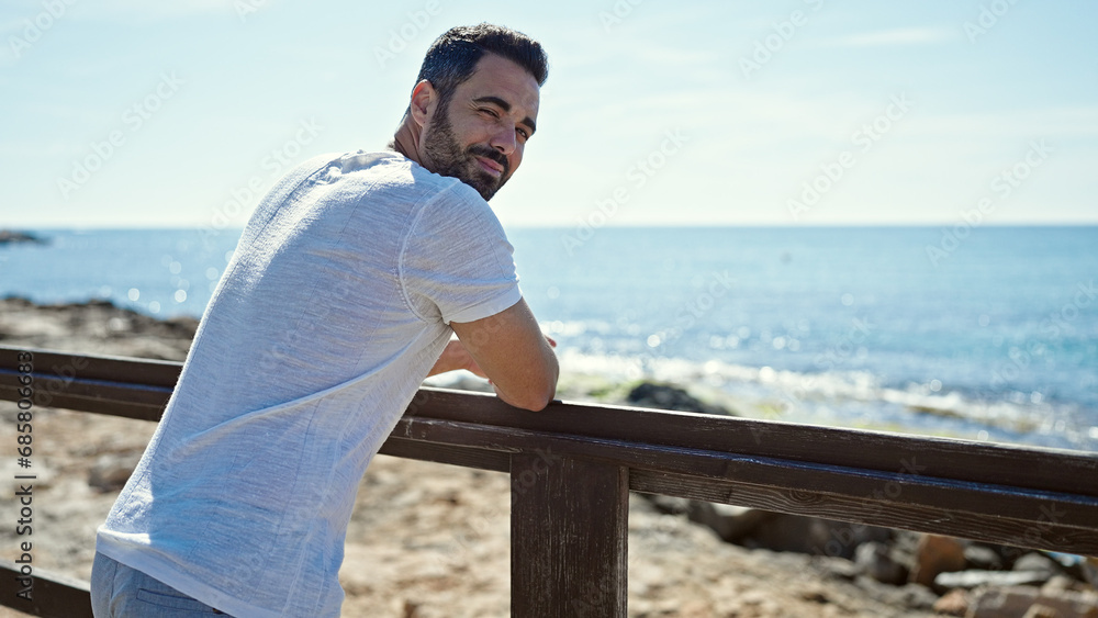 Young hispanic man smiling confident standing at seaside