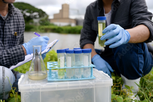 Environmental Engineers Inspect Water Quality, pH Test and Take Water sample notes in The Field Near Farmland, Fish Pond, Natural Water Sources that may be Contaminated by Suspicious Pollution Sites. photo