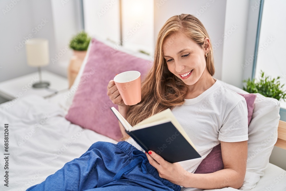 Young blonde woman drinking cup of coffee reading book at bedroom Young blonde woman drinking cup of coffee reading book at bedroom