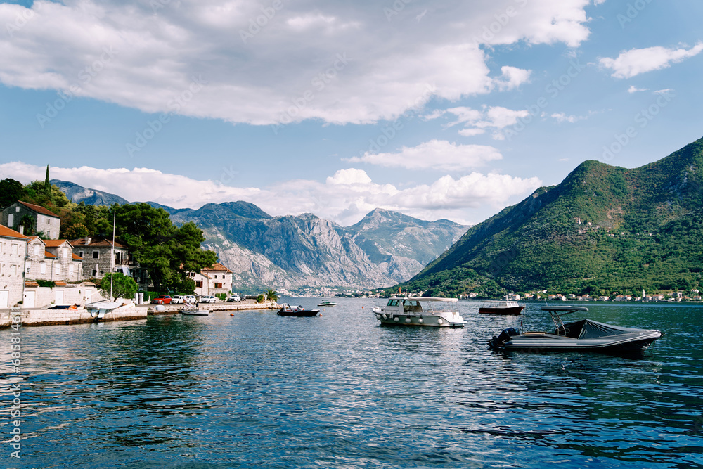Motor boats are moored off the coast of Perast against the backdrop of ancient houses at the foot of the mountains. Montenegro
