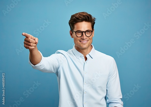 Portrait of a dressed young man of about 20 years old pointing his finger to the side on a blue background. Generated by AI. photo