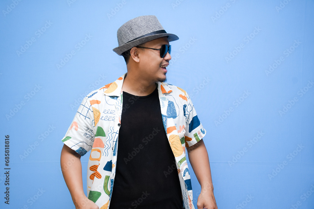 asian man wearing beach shirt pointing a finger to vacation discount offer. Isolated on blue background. Vacation concept asian man wearing beach shirt pointing a finger to vacation discount offer. Isolated on blue background. Vacation concept