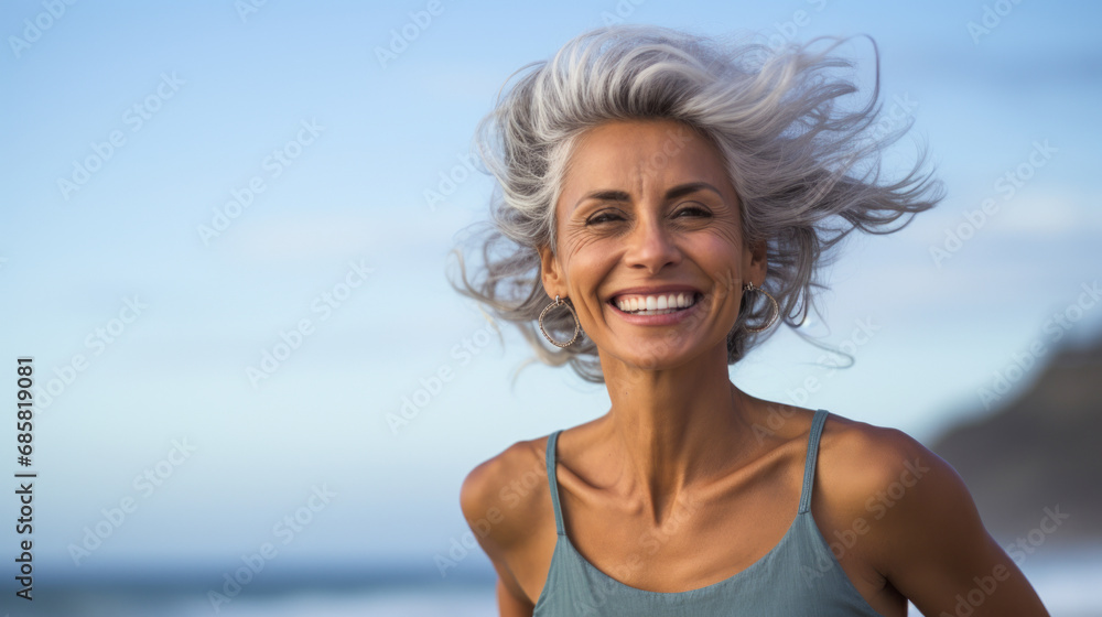 An exuberant senior woman with silver hair enjoying a lively moment on the beach, her hair flowing in the breeze at twilight. An exuberant senior woman with silver hair enjoying a lively moment on the beach, her hair flowing in the breeze at twilight.