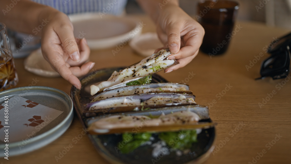 Young hispanic woman eating razor shells at the restaurant Young hispanic woman eating razor shells at the restaurant