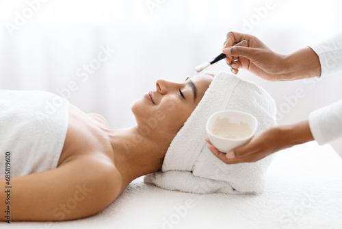 Young indian lady getting facial treatment at spa salon