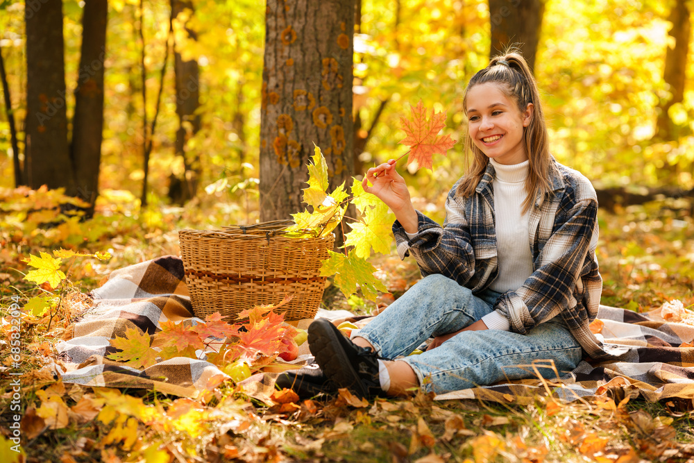 A young girl in the autumn forest is sitting on a plaid plaid and is enjoying the peace and sunshine, the beautiful atmosphere of autumn A young girl in the autumn forest is sitting on a plaid plaid and is enjoying the peace and sunshine, the beautiful atmosphere of autumn