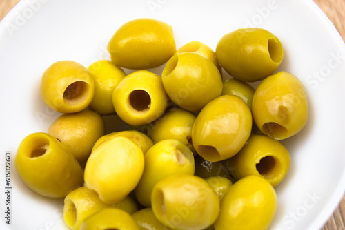 Green olives in a cup. Pitted green olives in a white cup on the table. Canned olives, recipe, food.
