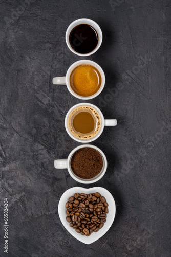 View from above. Some types of coffee in various cups arranged in a vertical row on a black background