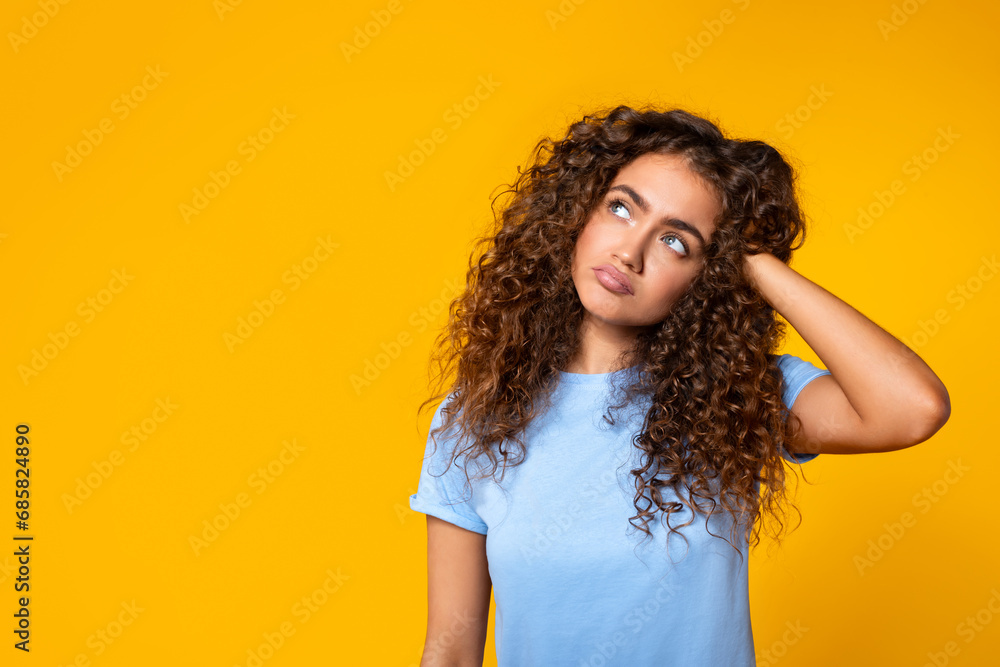 Curious woman with hand in hair looking aside at free space Curious woman with hand in hair looking aside at free space