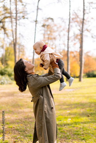 Young woman holding cute baby girl in the autumn park