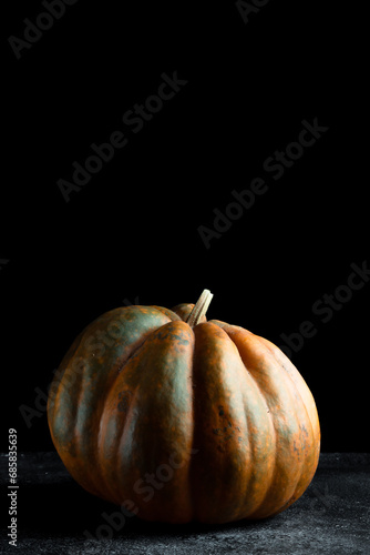 Fresh pumpkin on a dark background. Textured orange pumpkin. Autumn harvest. Ingredient for pumpkin pie.