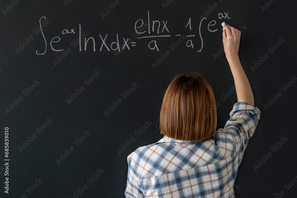 A young female student writes a complex mathematical formula on the blackboard A young female student writes a complex mathematical formula on the blackboard