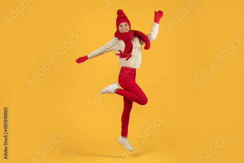lady in winter clothes leaping with joy on yellow backdrop