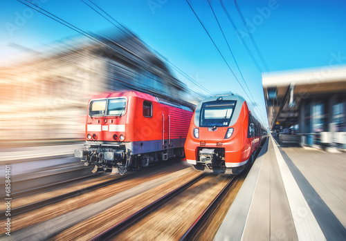 Red high speed trains in motion on the railway station at sunset. Fast modern intercity train and blurred background. Railway platform. Railroad in Germany. Commercial and passenger transportation